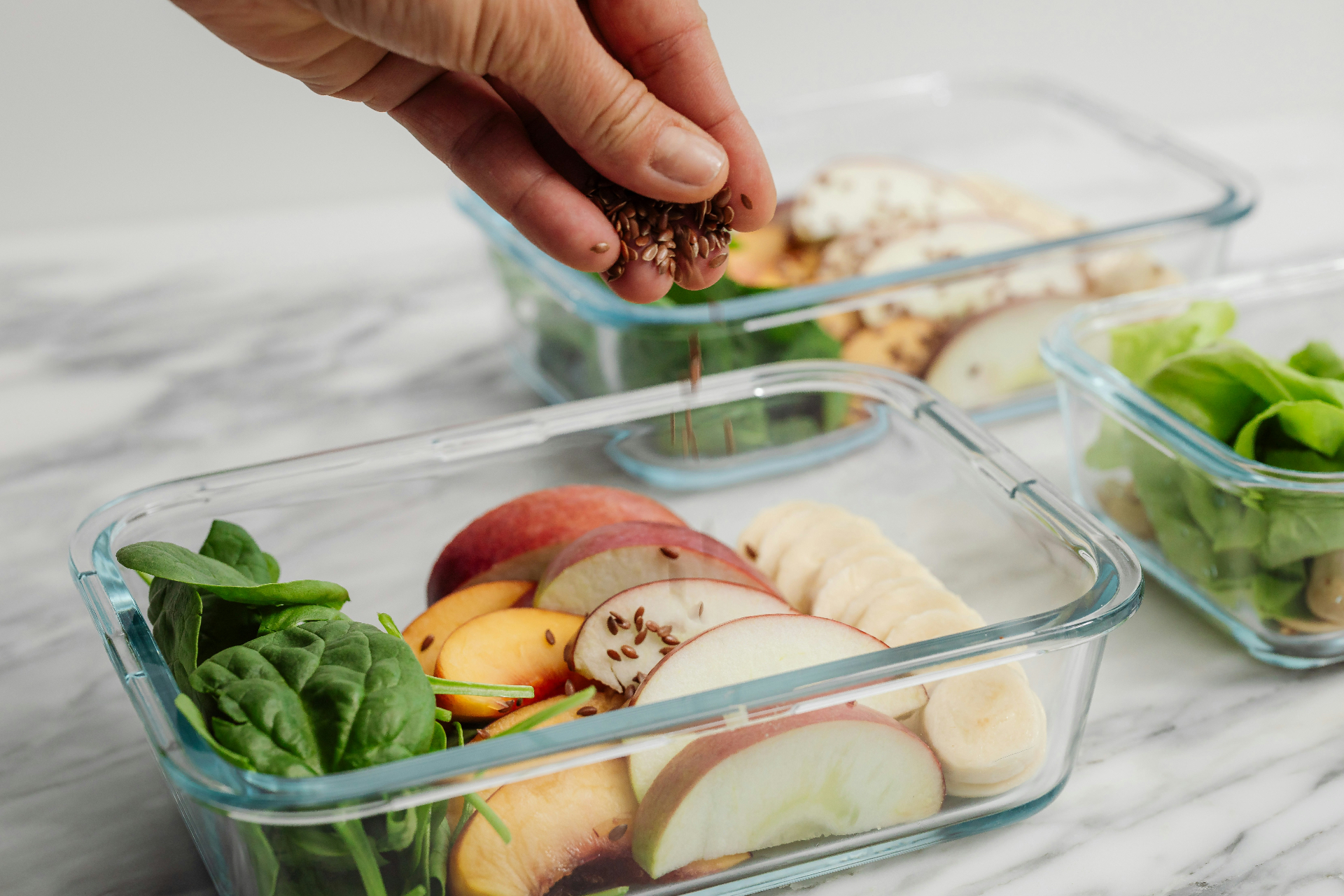 sprinkling flax seeds onto meal-prep containers